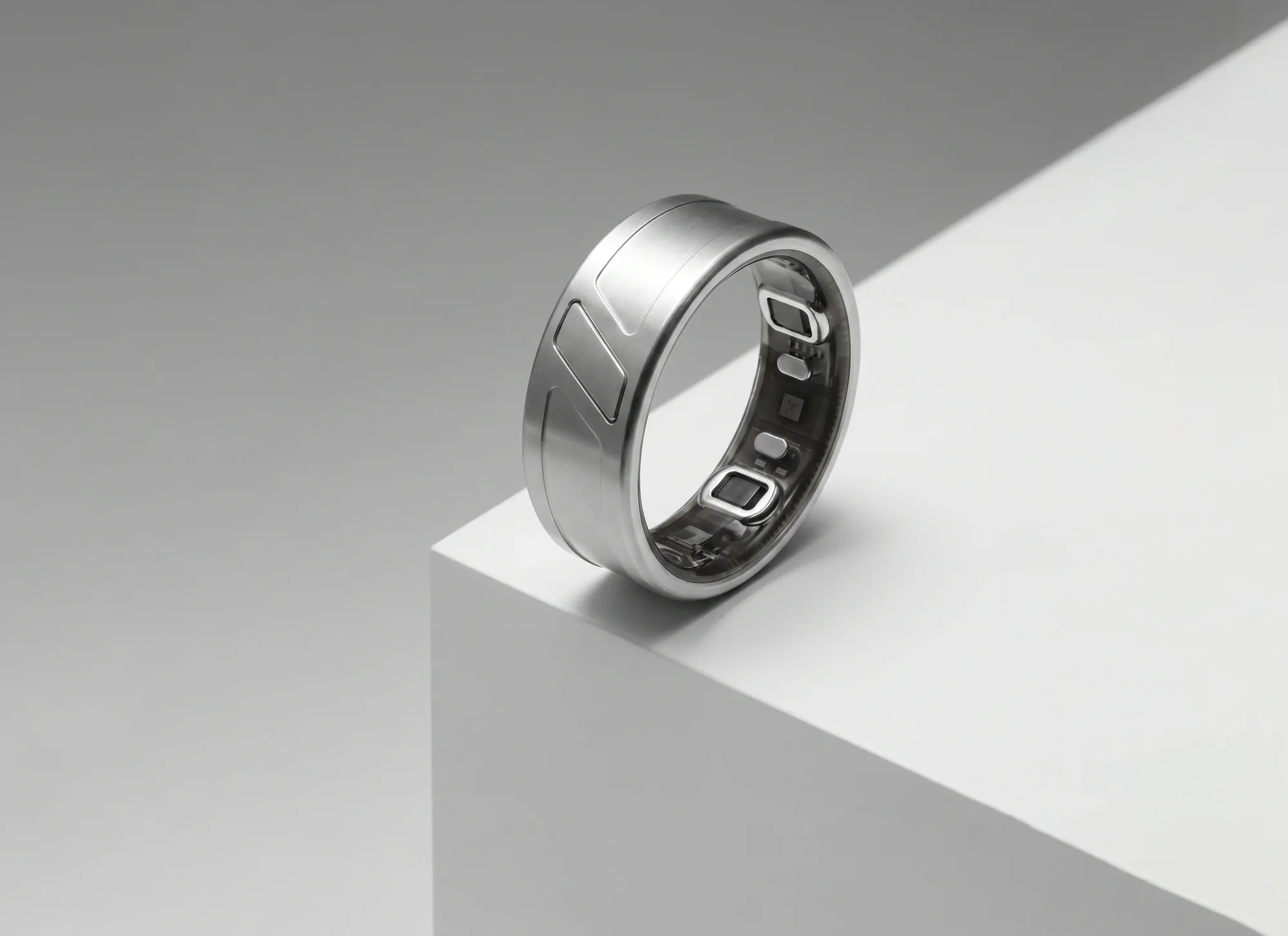 The silver-tone Mere Ring resting on the edge of a white block, its sensors visible inside the band